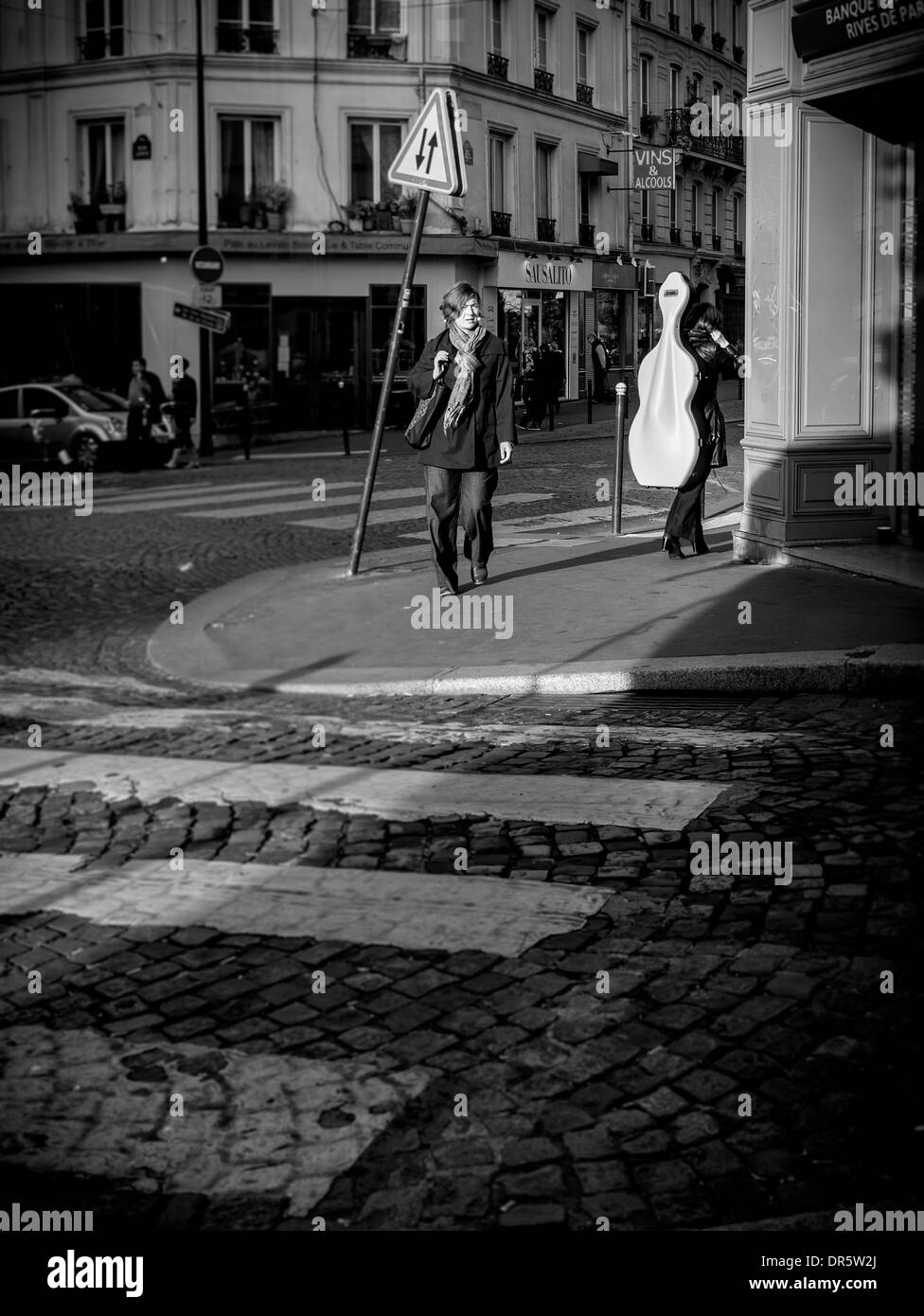 girl carrying a chello walks through montmartre paris france Stock Photo