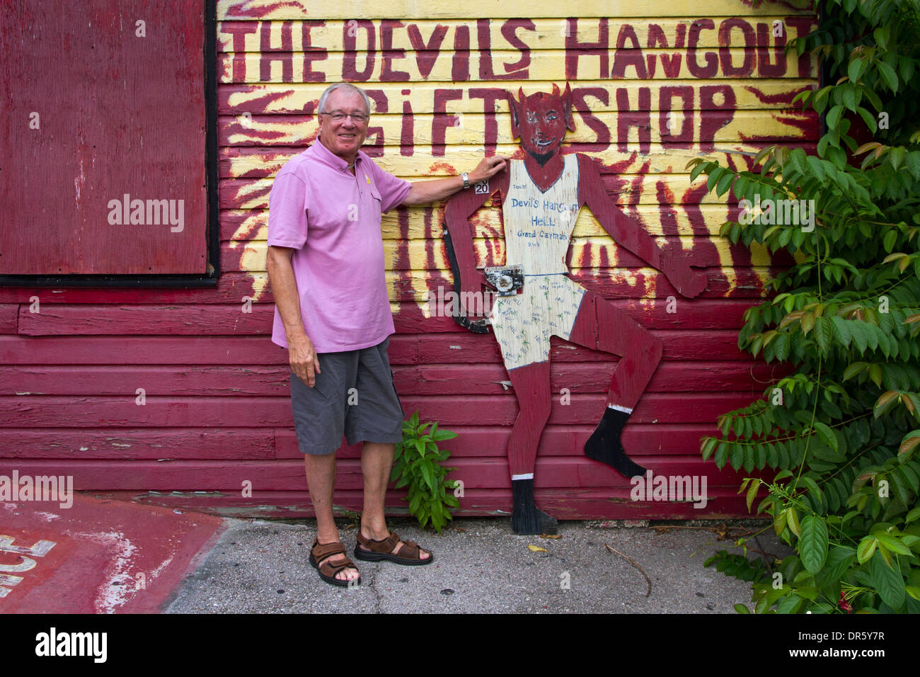 Tourist flirting with the devil outside Hell's Hangout Gift Shop on Grand Cayman Island Stock Photo