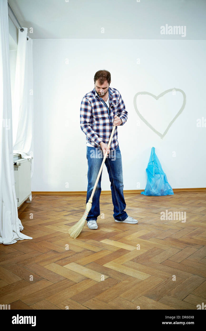 Man sweeping the parquet floor, heart shape on the wall, Munich, Bavaria, Germany Stock Photo