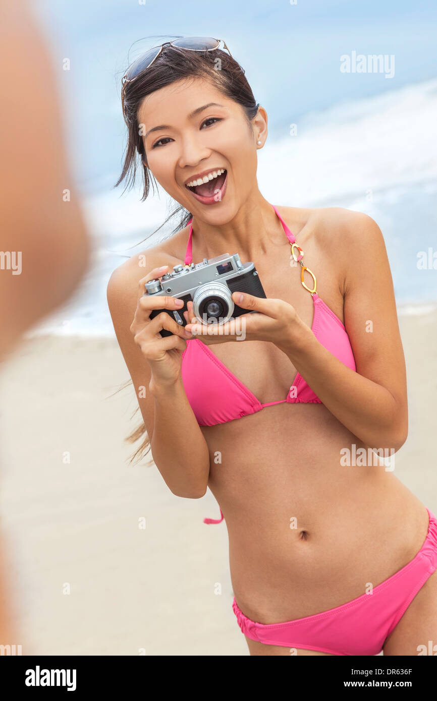 Asian Chinese girl or young woman in pink bikini at beach looking happy  taking picture or photograph with retro digital camera Stock Photo - Alamy