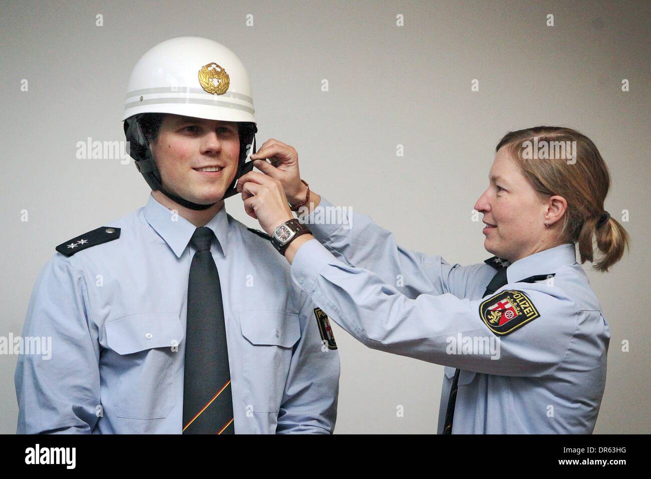 Mainz, Germany. 20th Jan, 2014. Police officer Anette Stacher helps her colleague matthias Zindel put ona police helmet from Japan at the police headquarters in Mainz, Germany, 20 January 2014. The police headquarters made it into the Guinness Book of Records with their collection of 519 police hats. Photo: FREDRIK VON ERICHSEN/dpa/Alamy Live News Stock Photo