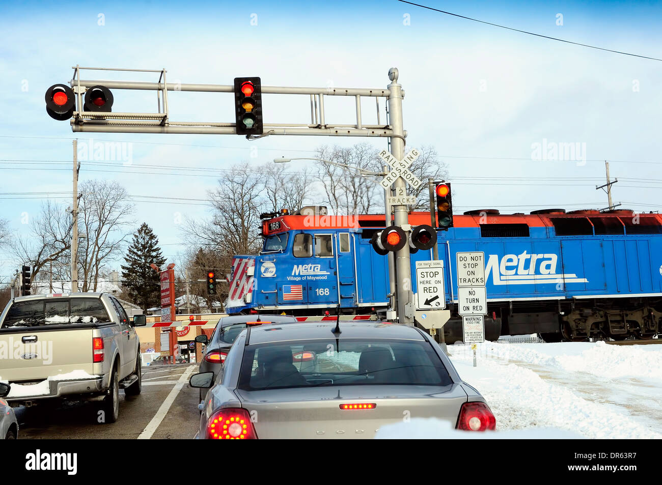Cars stopped at commuter train crossing as engine speeds by Stock Photo Alamy