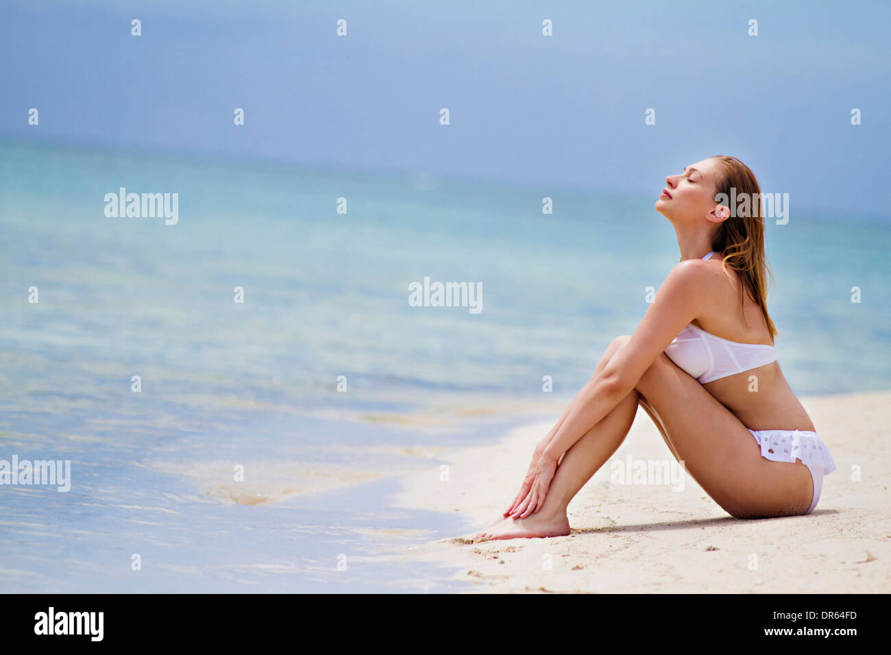 Young woman in bikini relaxes on beach, Lankayan Island, Borneo