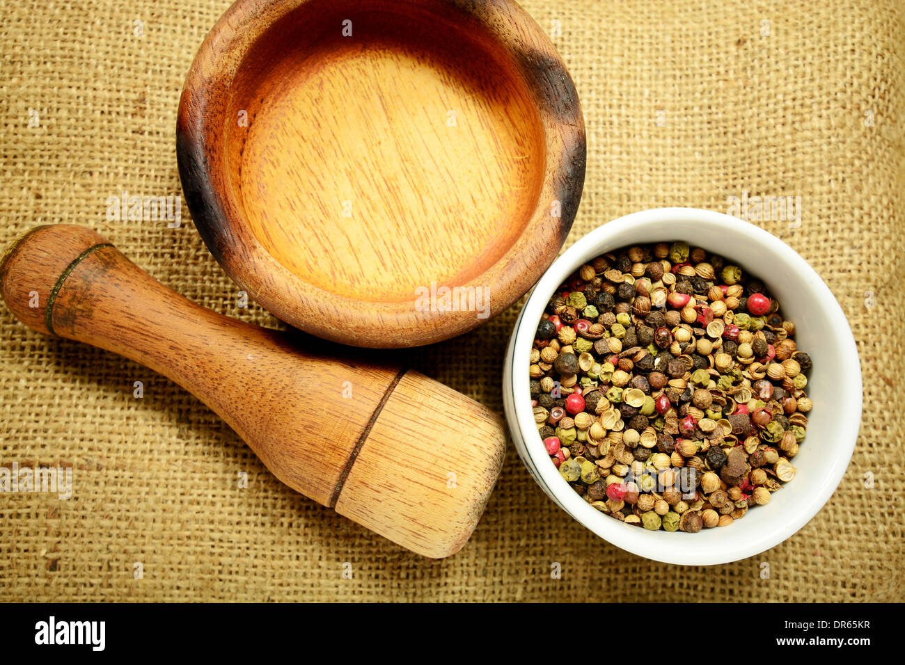 Macro shot of peppercorns and a wooden grinder and grinding bowl Stock Photo