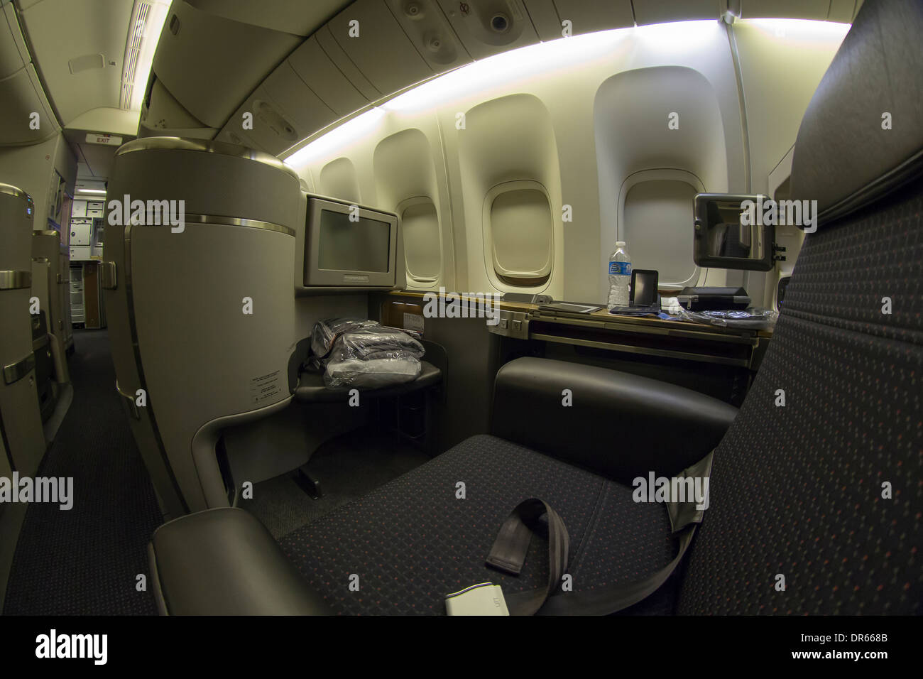 A commercial airline's fully flat first class seat and modern entertainment system, duvet bed, and fine cuisine. Stock Photo