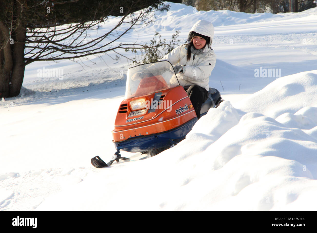 A woman in her early 30s enjoying a snowmobile ride after a fresh snowfall in Quebec, Canada. Stock Photo