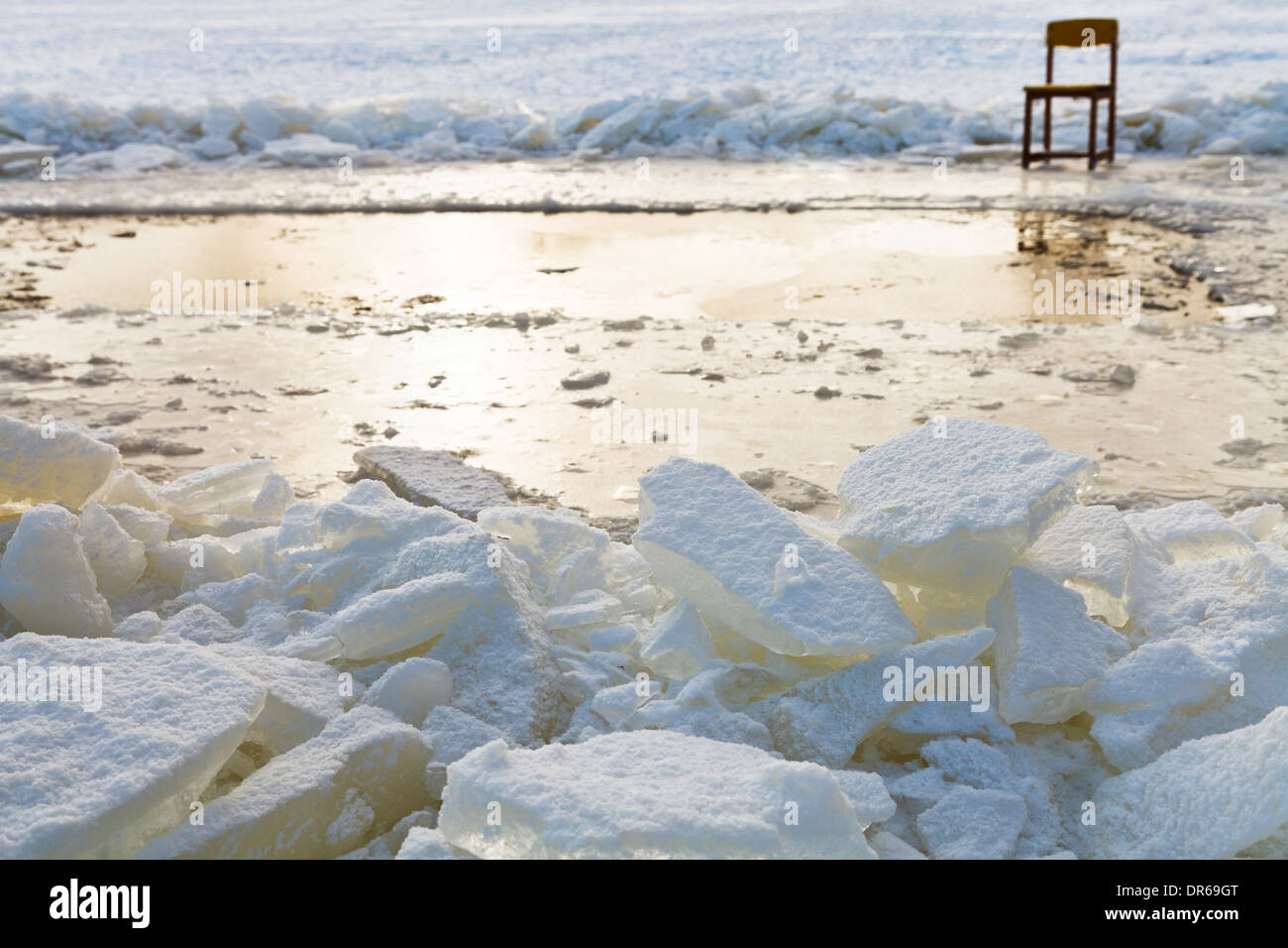 ice blocks and chair on edge of ice-hole in frozen lake in winter Stock Photo