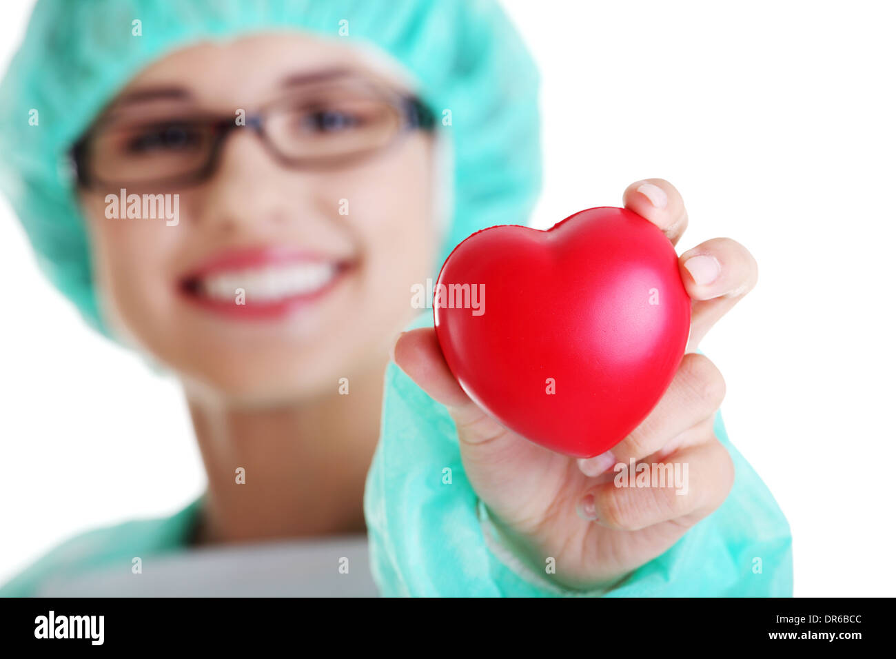 Smiling female doctor or nurse in surgical clothes holding red heart ...