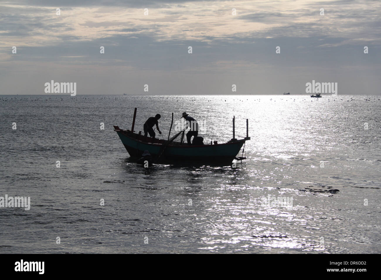 Silhouette of fishermen on a boat at sunset Stock Photo - Alamy