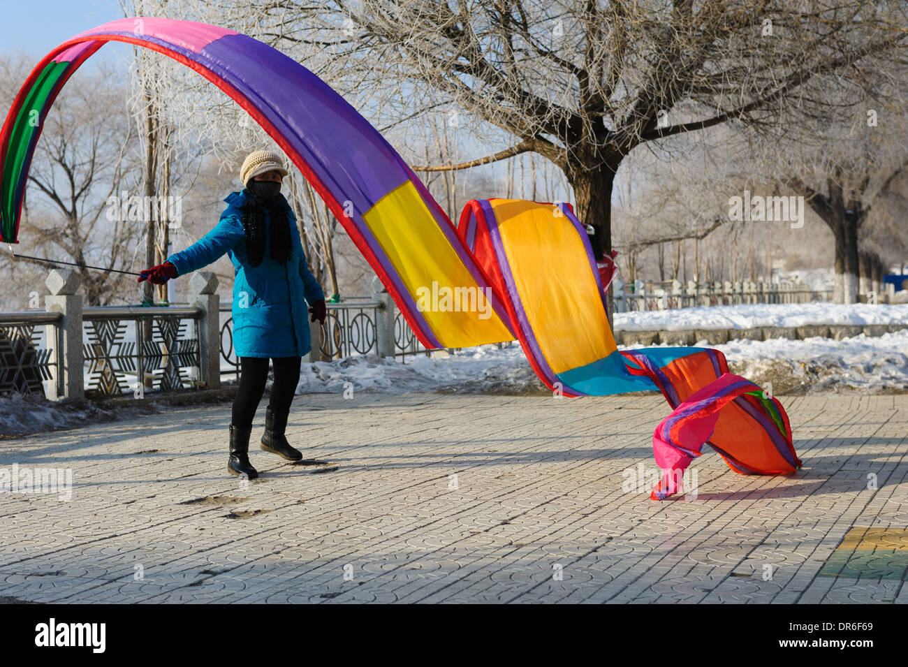 Woman performing a Chinese ribbon dance under the frost covered trees