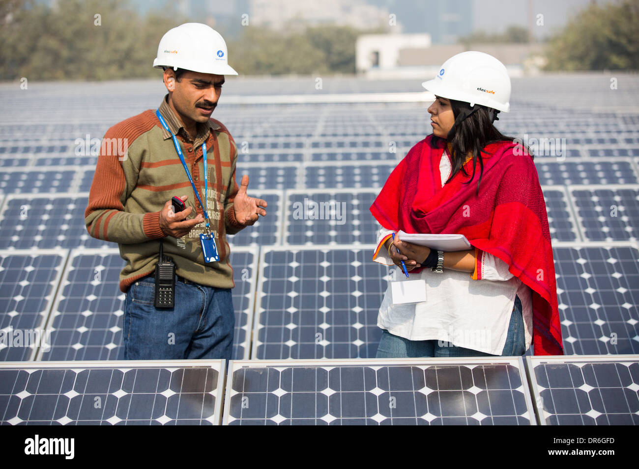Workers at a 1 MW solar power station run by Tata power on the roof of an electricity company in Delhi, India. Stock Photo