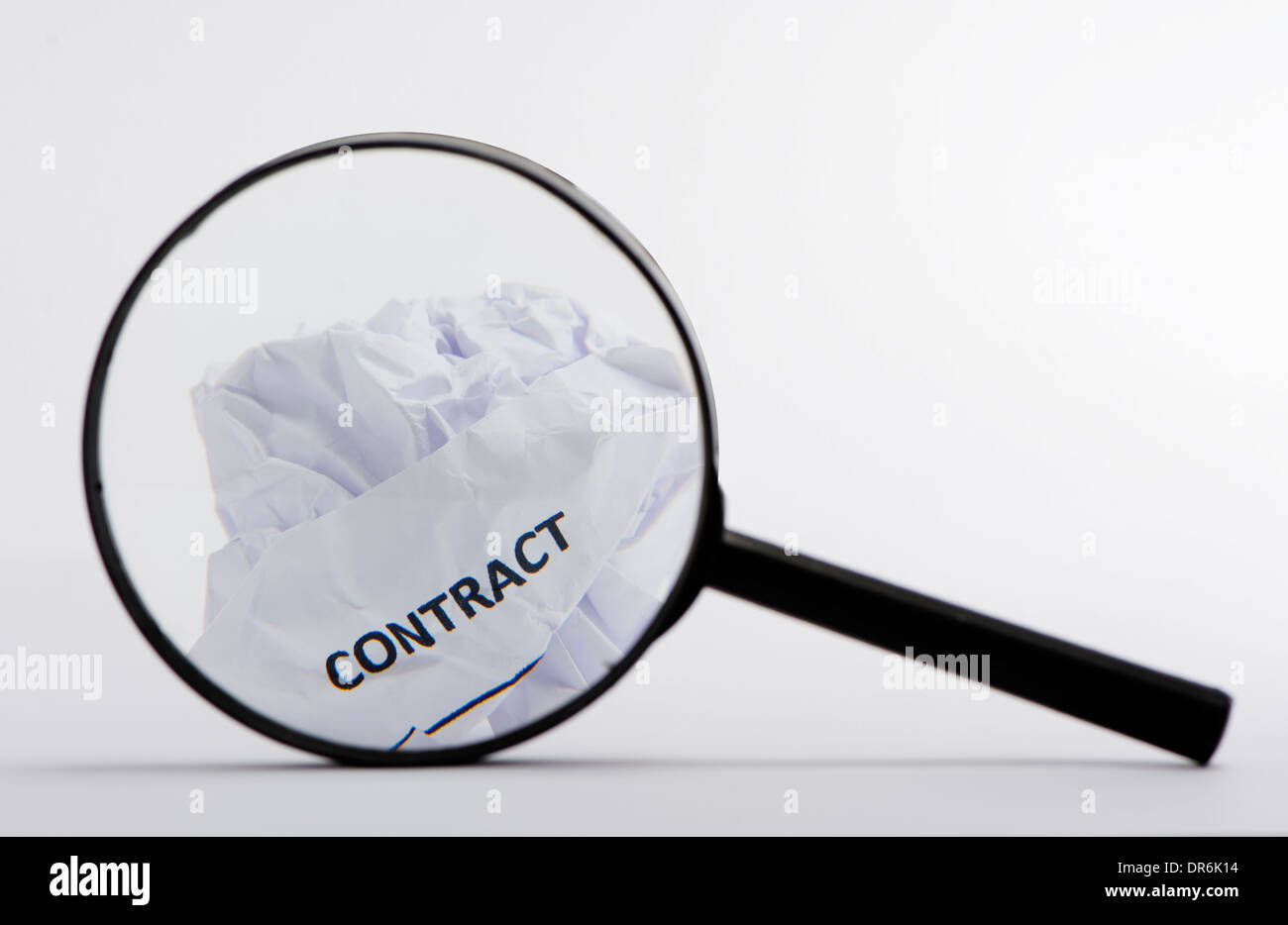 Contract On A Crumpled Ball Of Paper Viewed Through Magnifying Glass Stock Photo