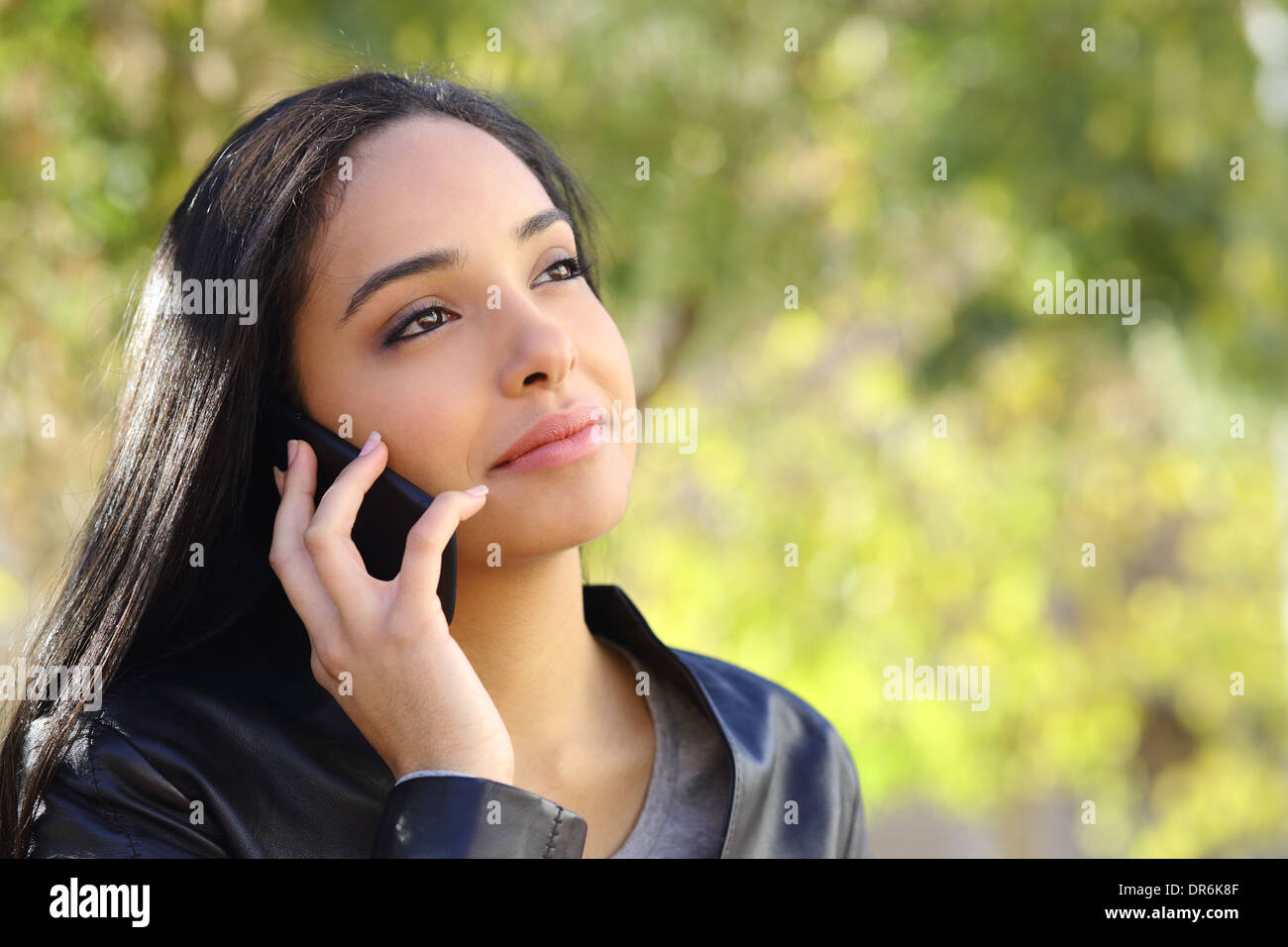 Arab business woman on the mobile phone in a park with a green background Stock Photo