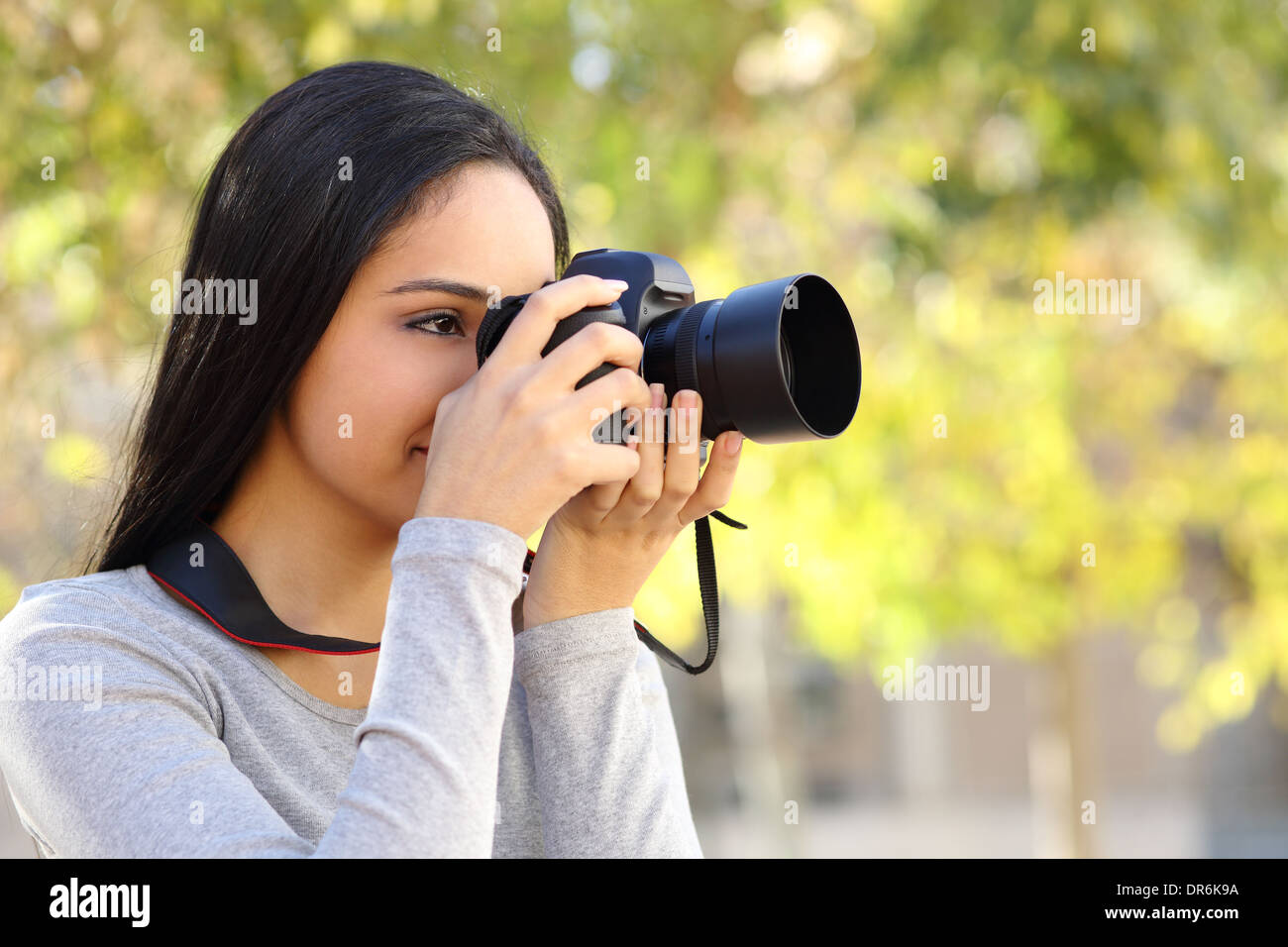 Photograph woman learning photography in a park happy with a green unfocused background Stock Photo