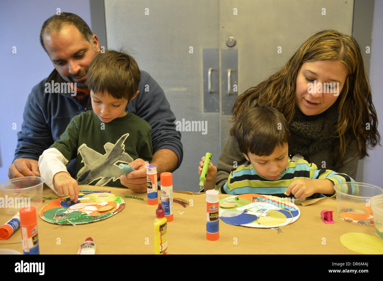 Garden City, New York, U.S. January 20, 2014. L-R, JESSE RIVERA; son JADEN RIVERA, 4; wife ALEXANDRA RIVERA; and son JACOB RIVERA, 5, of Sea Cliff, create artwork of peace at the program Dreaming with Dr. Martin Luther King, Jr. where children also explored Dr. King's life, at the Long Island Children's Museum, to celebrate the American official federal holiday Birthday of Martin Luther King, Jr. Stock Photo