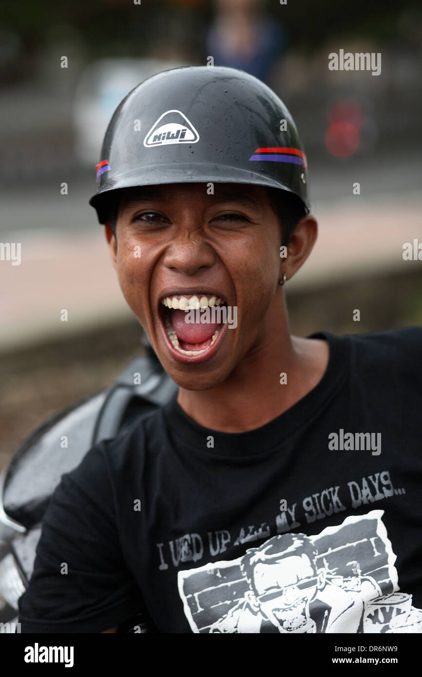Smiling Indonesian young college student wearing black t-shirt and black helmet. Kupang, West Timor, Indonesia. Nov 2005 Stock Photo