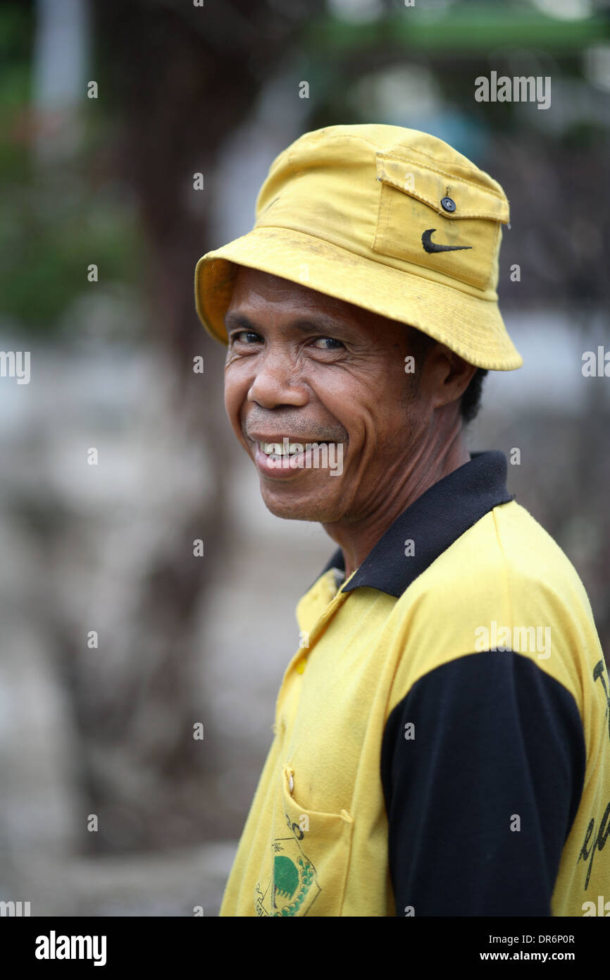 Smiling Indonesian man wearing yellow shirt and yellow hat.  Kupang, West Timor, Indonesia. Nov 2005 Stock Photo