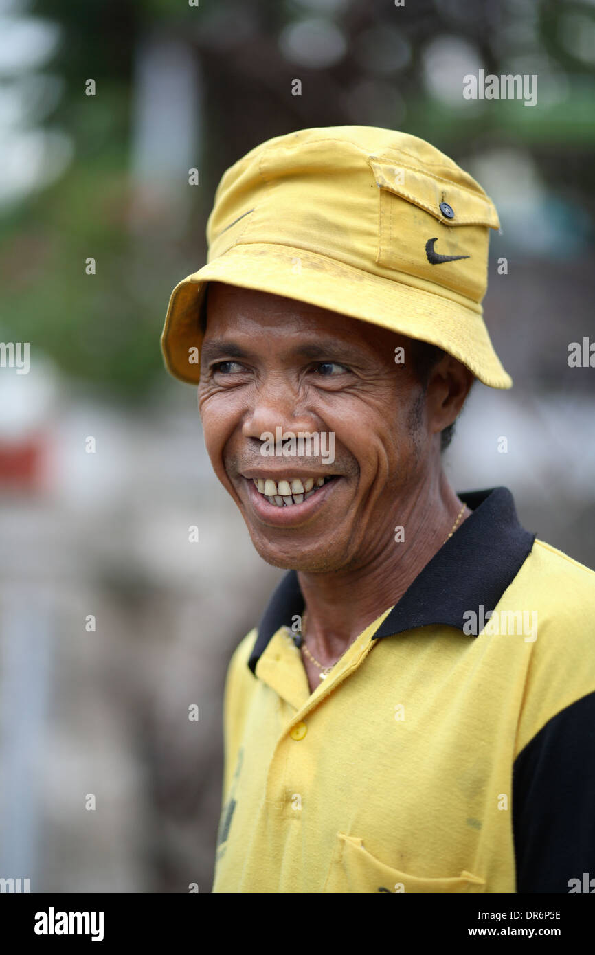 Smiling Indonesian man wearing yellow shirt and yellow hat.  Kupang, West Timor, Indonesia. Nov 2005 Stock Photo