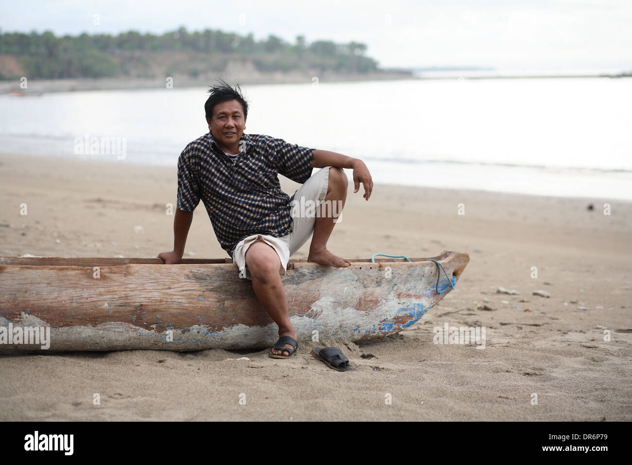 Man sitting on a canoe on the beach of Kupang, West Timor, Indonesia. Nov 2005 Stock Photo