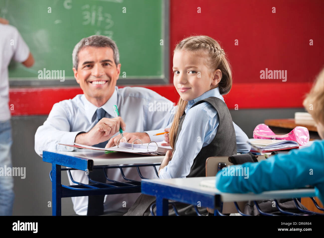 Girl And Teacher Sitting At Desk In Classroom Stock Photo - Alamy