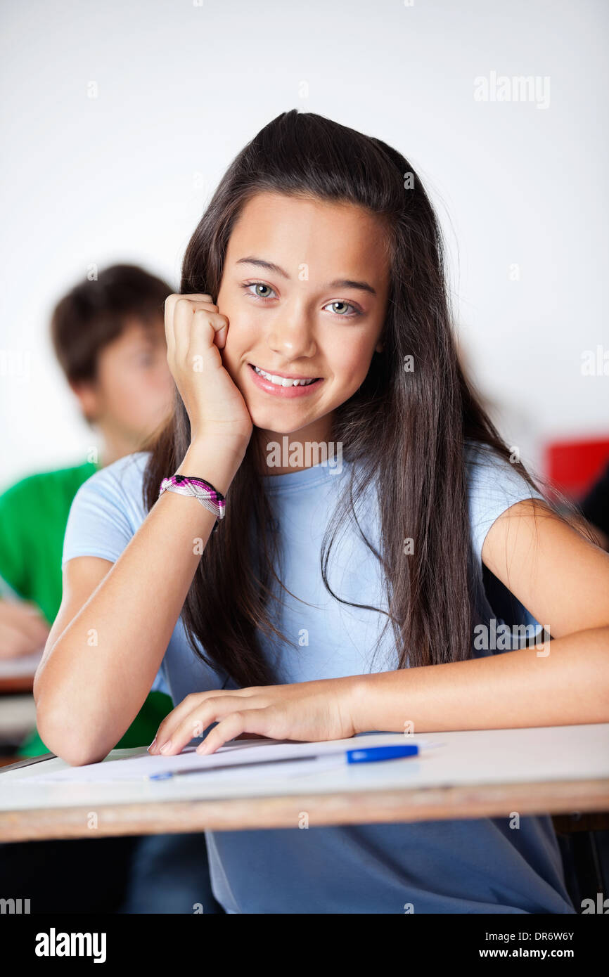 Happy Schoolgirl Sitting At Desk In Classroom Stock Photo - Alamy