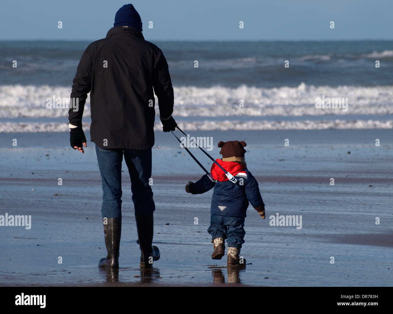Child on reins at the beach, Cornwall, UK Stock Photo