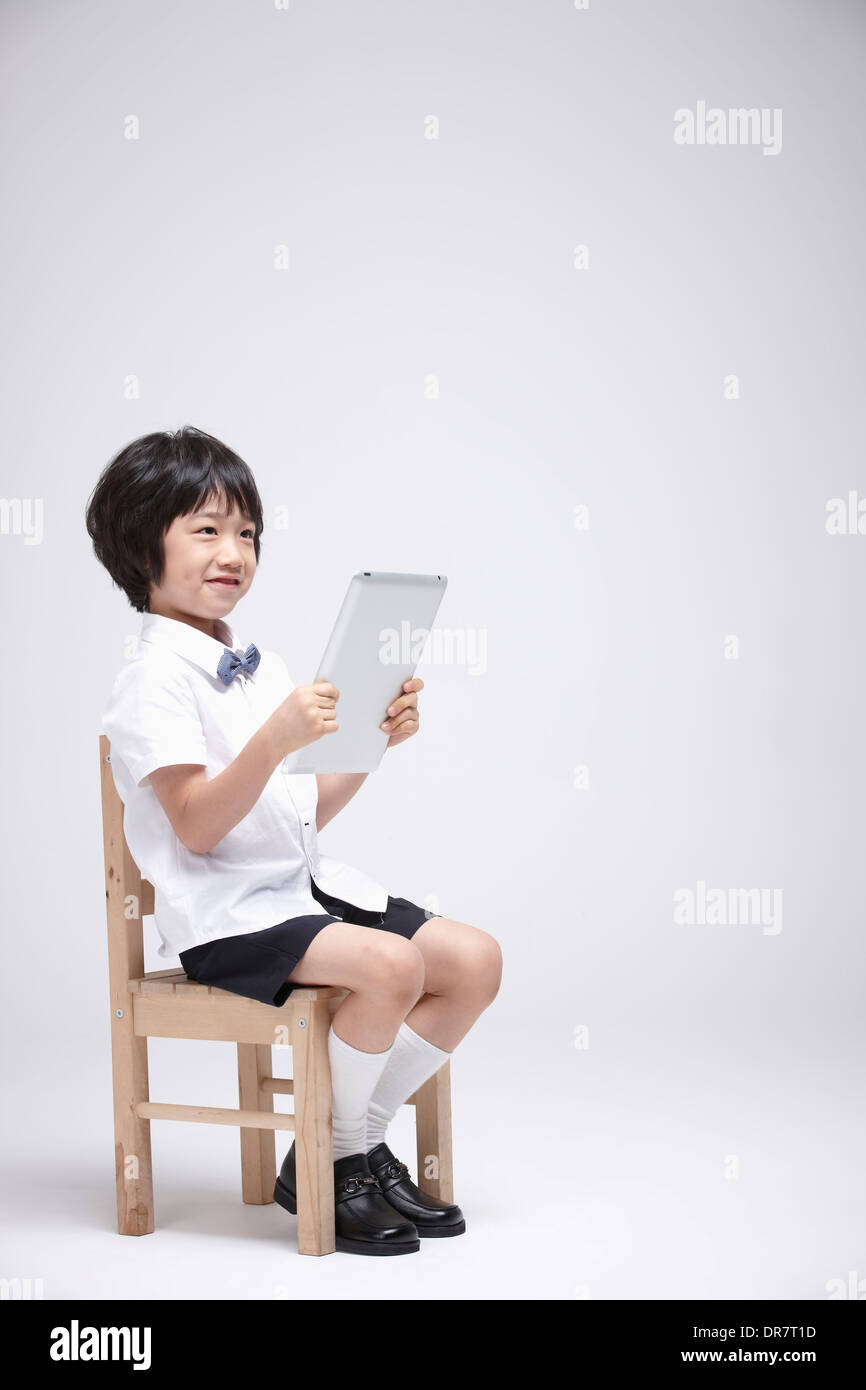 a boy using tablet PC on a chair Stock Photo