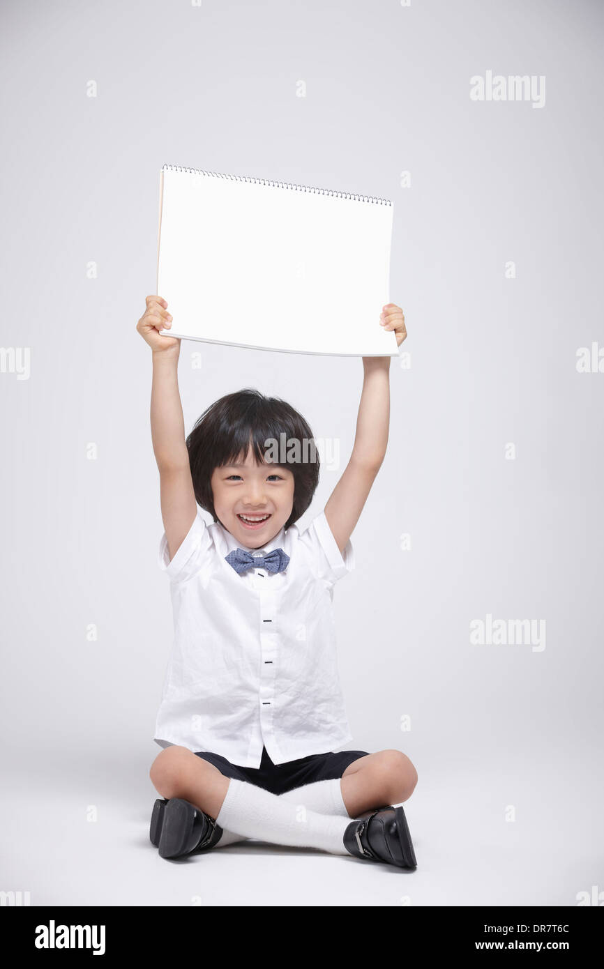 a boy sitting on the floor holding a blank sketch book Stock Photo - Alamy