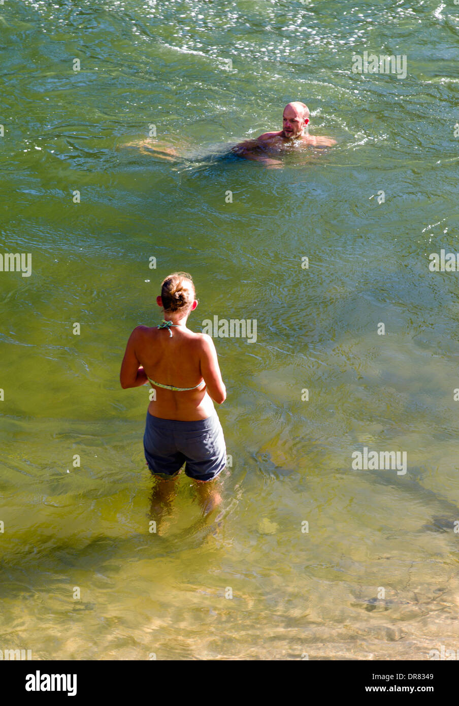 Woman wading and man swimming in the Arkansas River, which runs through