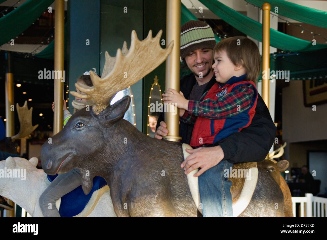 Father with Young Son Riding a Moose on a Carousel Stock Photo