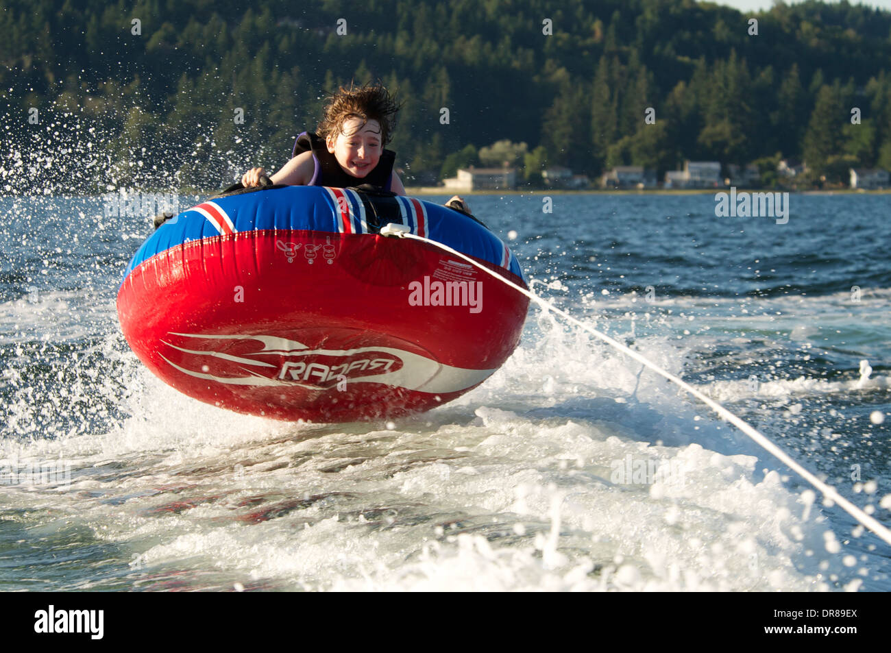 Boy joyfully and fearlessly rides inner tube on lake on a sunny summer