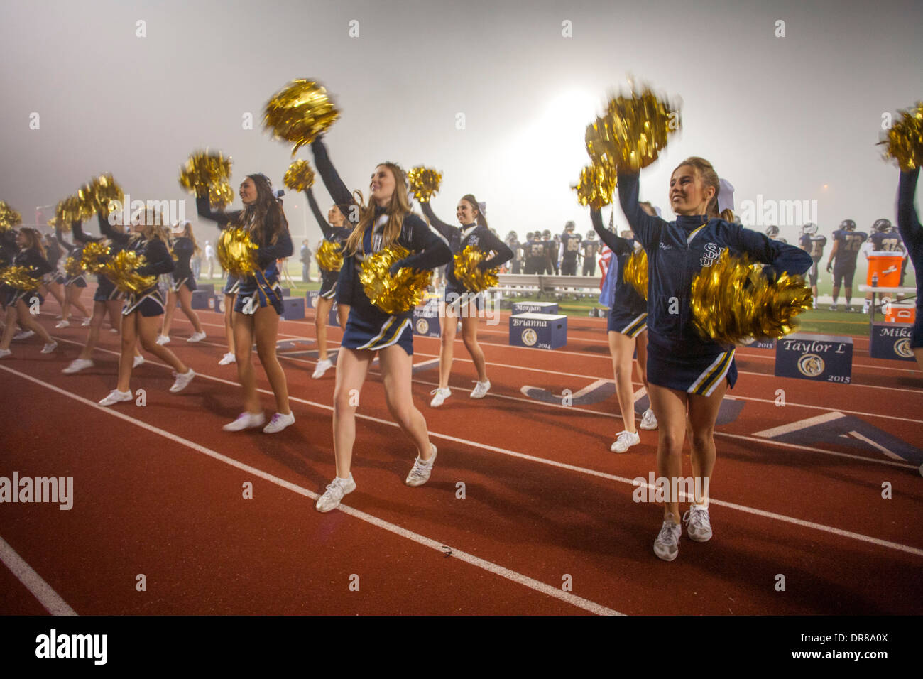 Cheerleaders entertain the spectators at a high school night football game in San Juan Capistrano, CA. Stock Photo