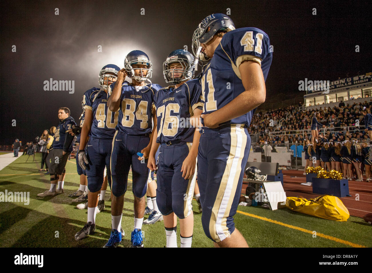 High school football players talk on the sidelines during a night game in San Juan Capistrano, CA. Stock Photo