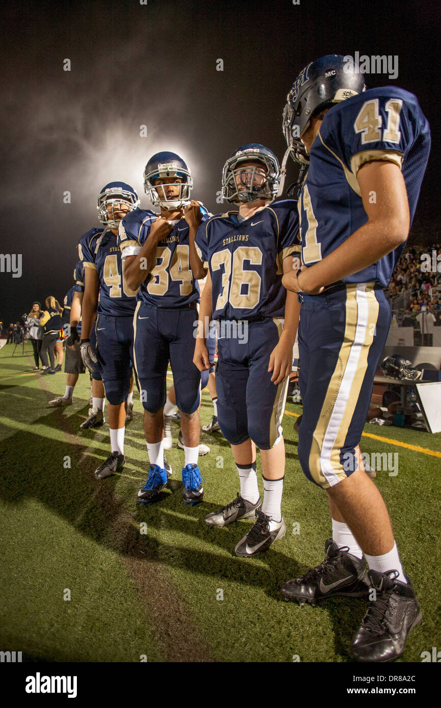 High school football players talk on the sidelines during a night game in San Juan Capistrano, CA. Stock Photo