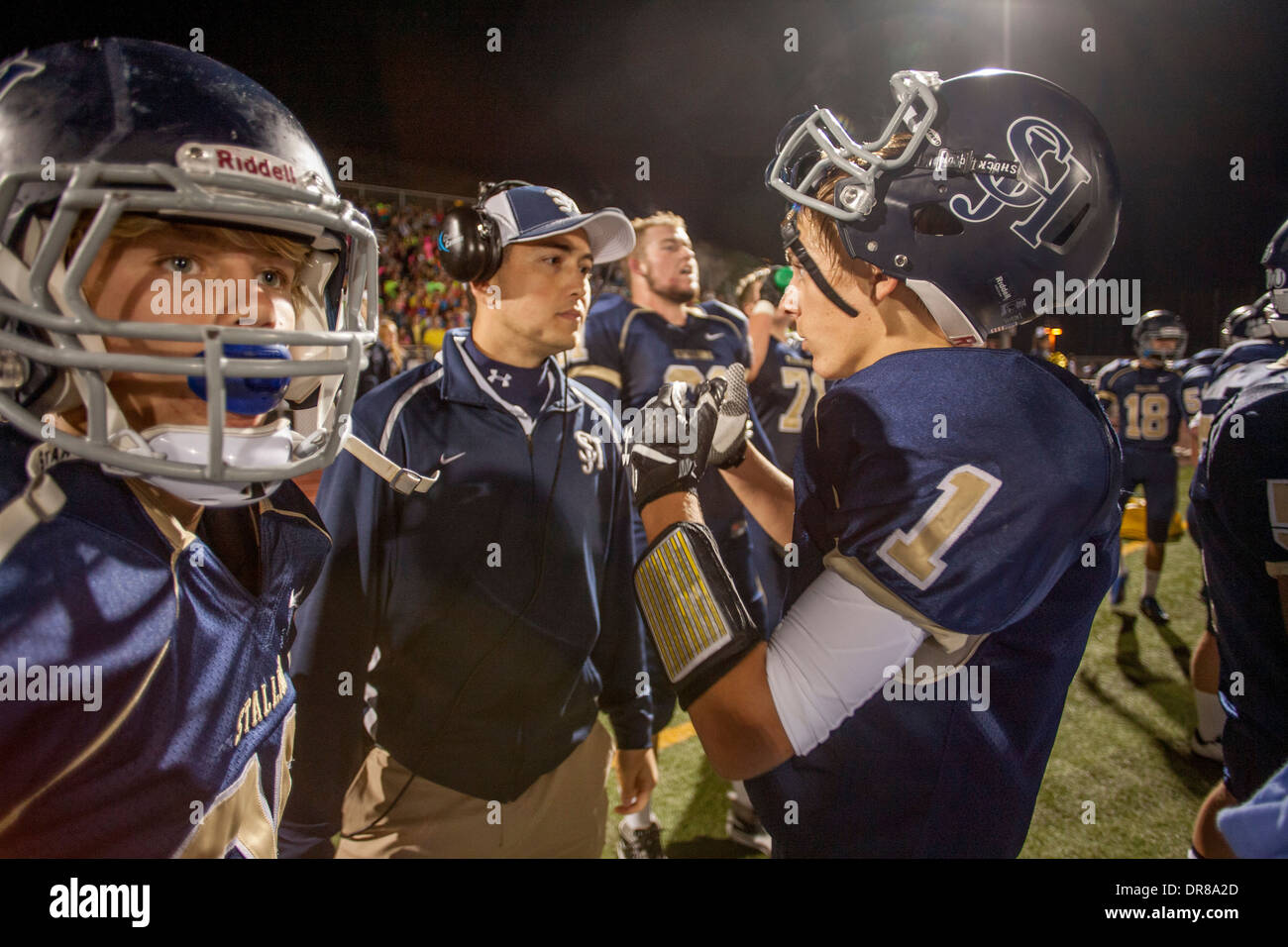 A high school football coach counsels his players on the sidelines at a night game in San Juan Capistrano, CA. Stock Photo