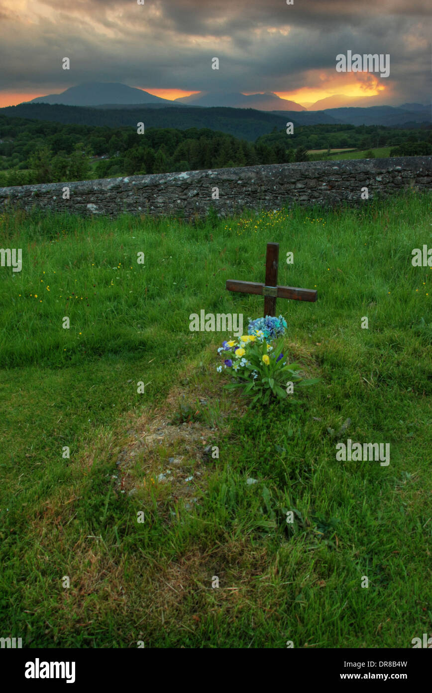 A marked grave with the sunset over Snowdonia in the distance Stock Photo