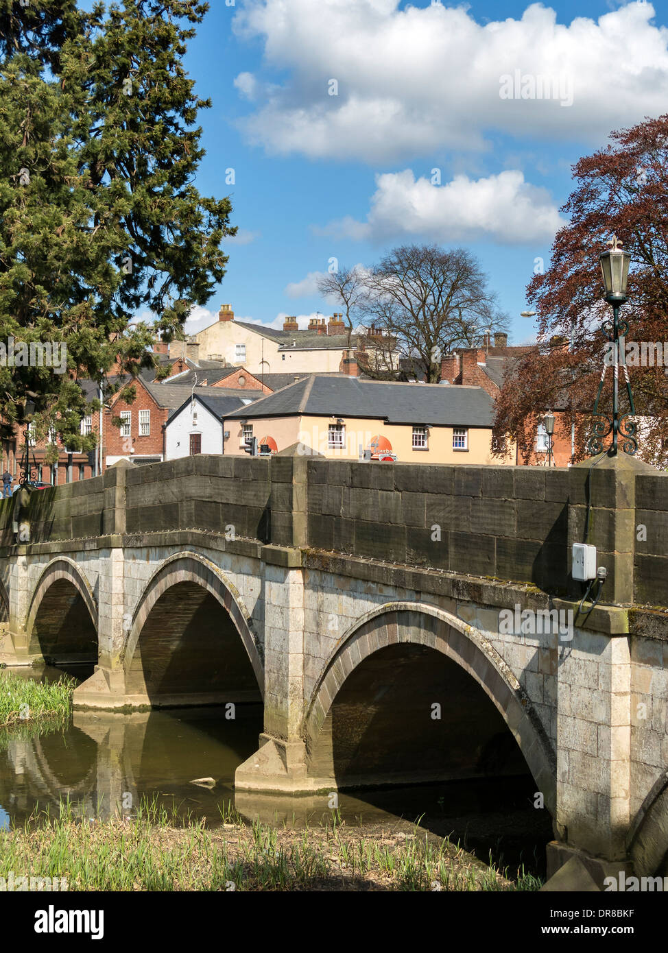 The stone arches of Lady Wilton bridge, over the River Eye with town centre buildings beyond, Melton Mowbray. Stock Photo