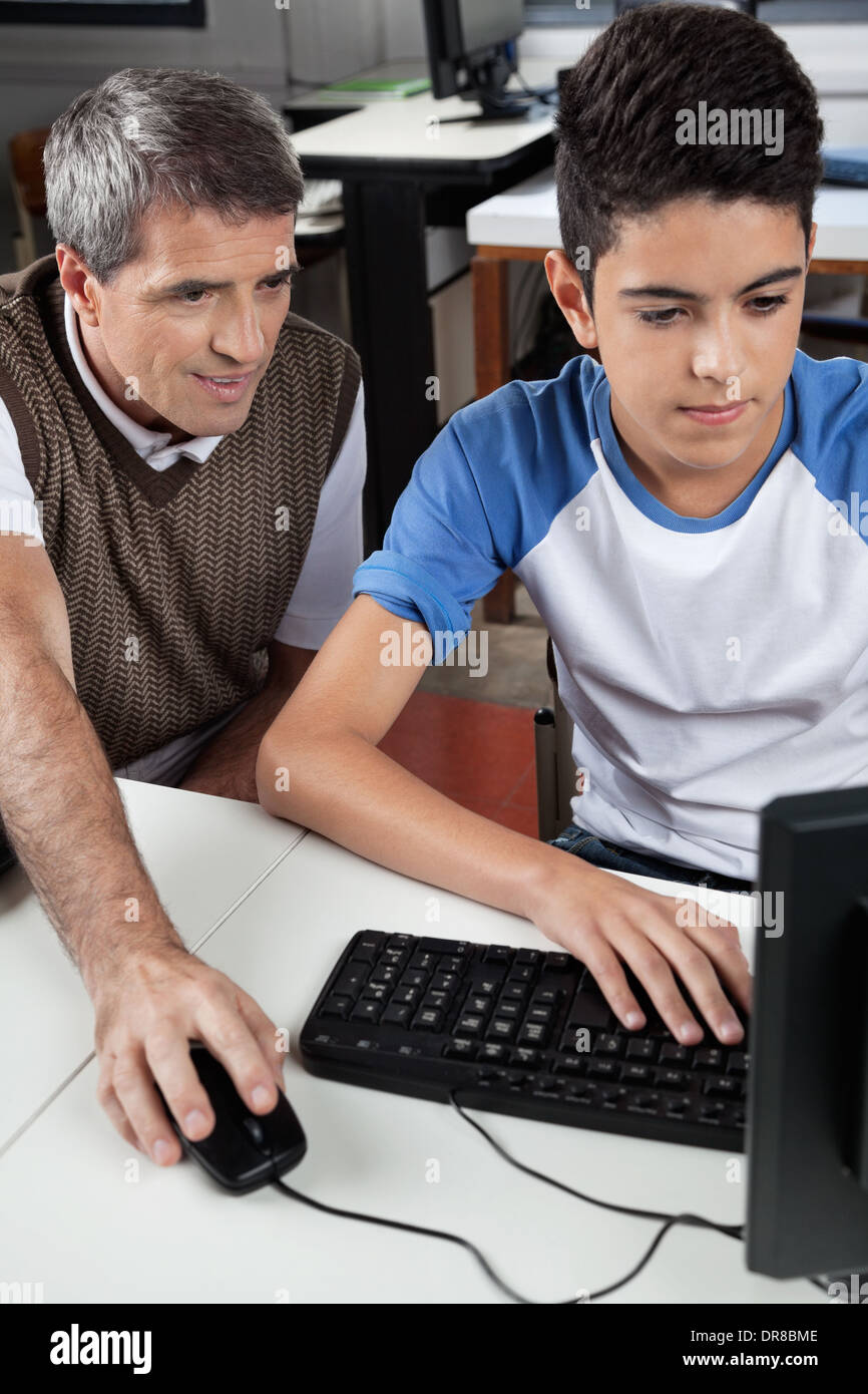 Teacher With Male Student Using Computer At Desk Stock Photo - Alamy