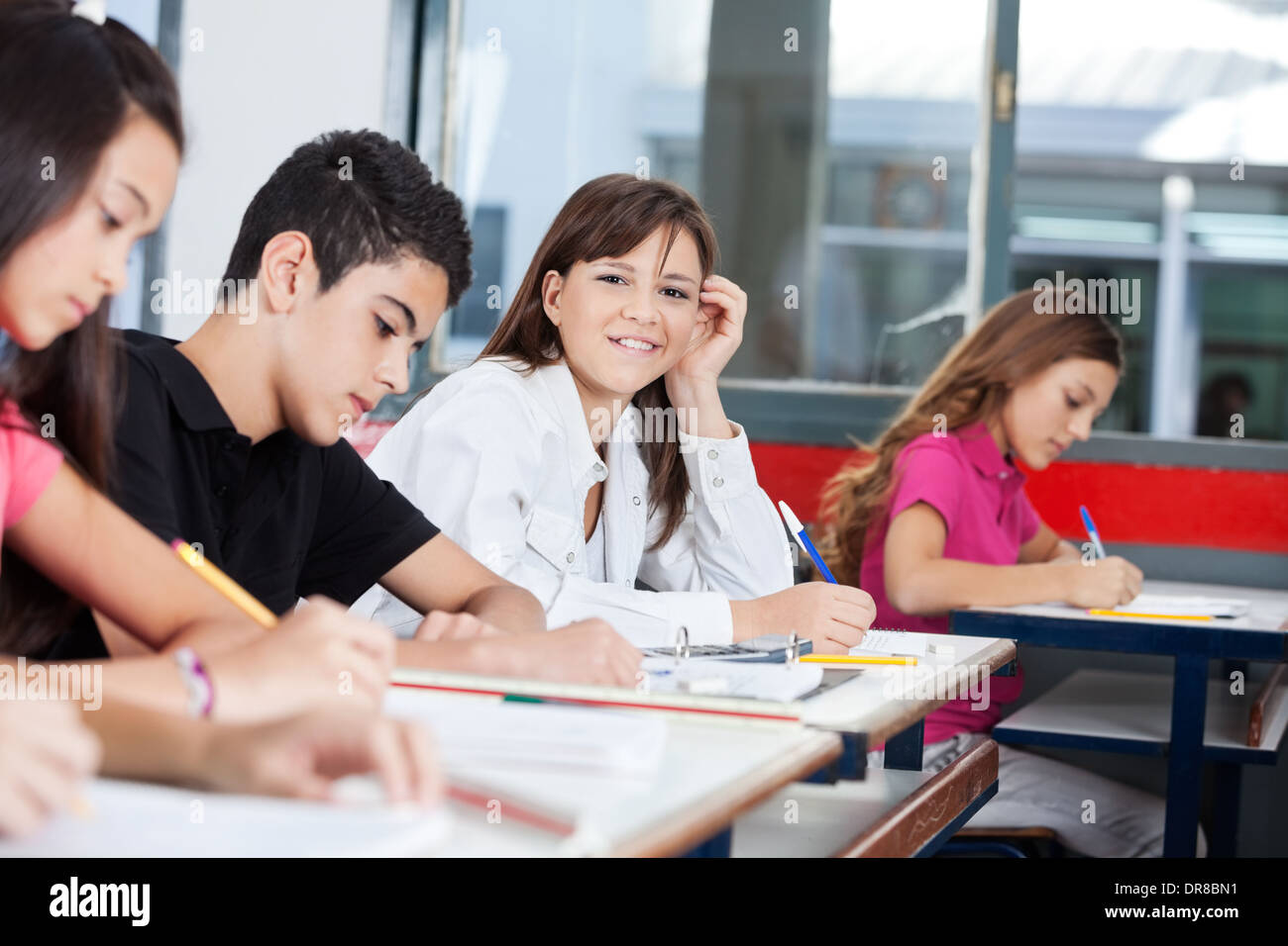 Teenage Girl With Friends Writing At Desk Stock Photo - Alamy