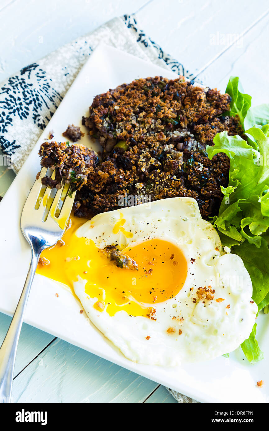 Healthy meal of black bean cake with mixed greens and a fried egg Stock