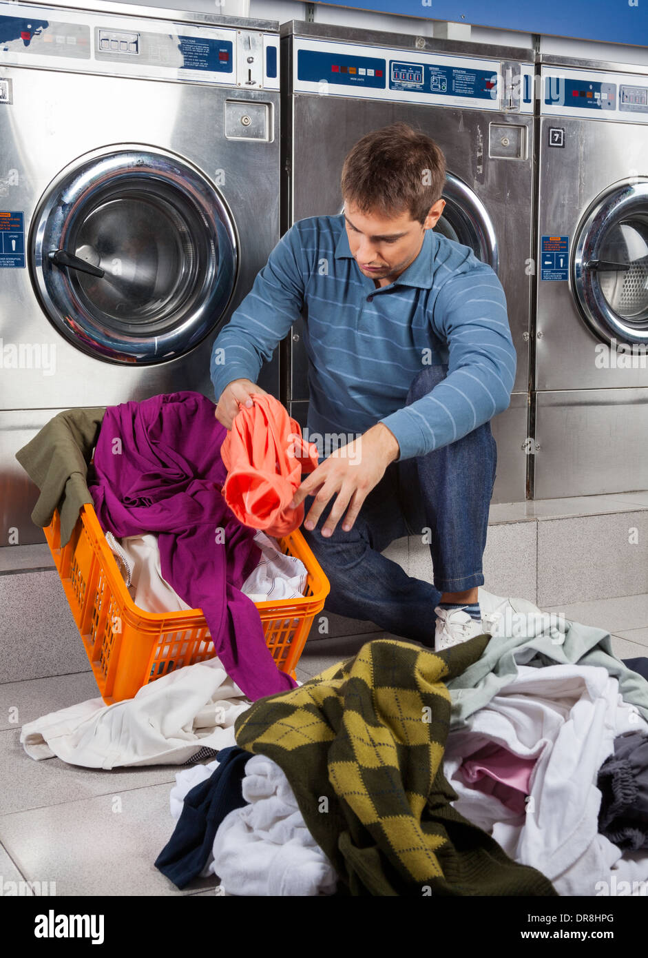 Man Putting Dirty Clothes In Basket at Laundromat Stock Photo 65957768