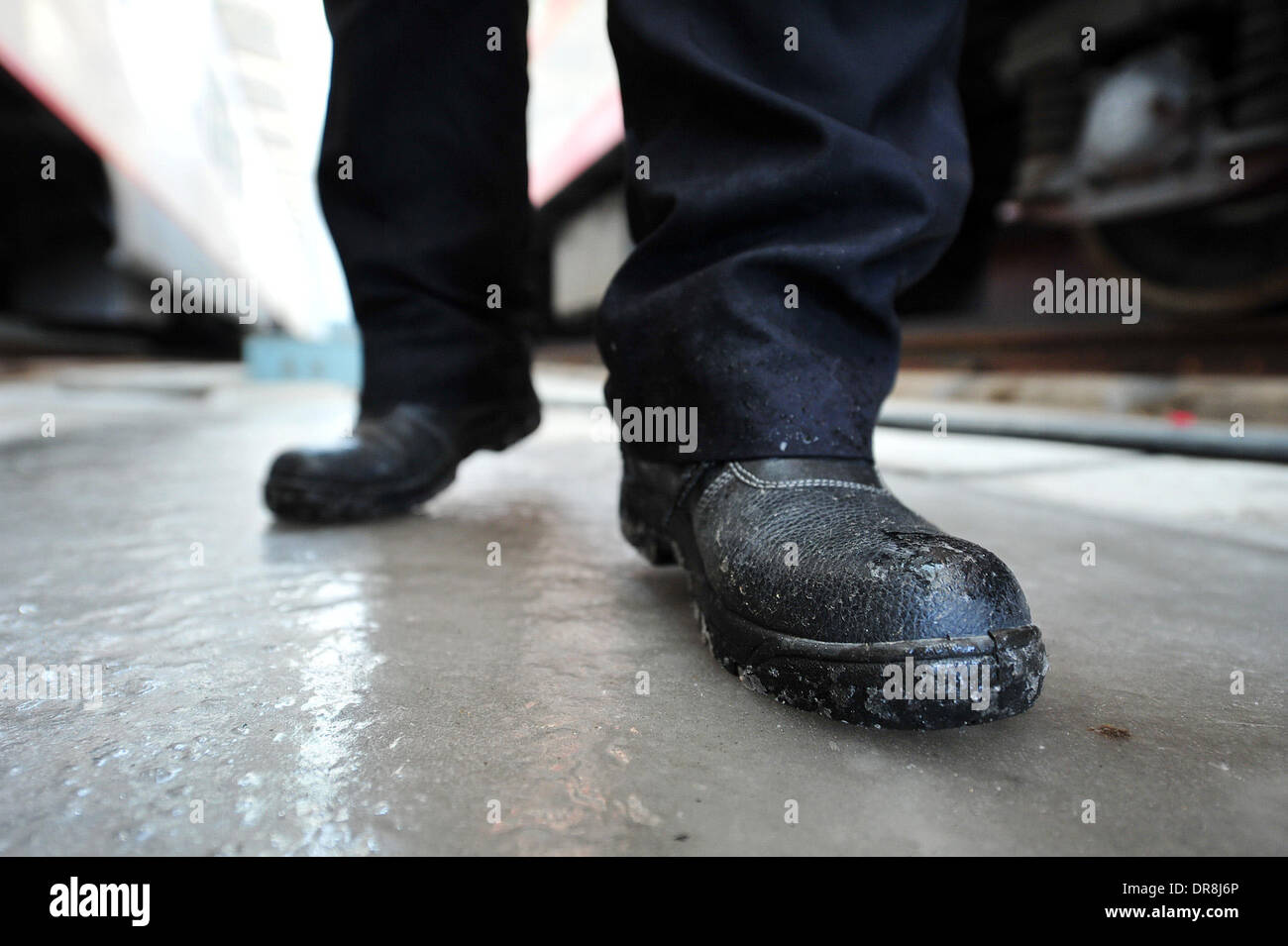 Yinchuan, China. 20th Jan, 2014. A support crew member walks on the frozen ground as he replenishes water supply for a passenger train at Yinchuan Railway Station in Yinchuan, capital of northwest China's Ningxia Hui Autonomous Region, Jan. 21, 2014. It is estimated that over a million passengers will travel by trains operated by the Yinchuan passenger section of the Lanzhou Railway Bureau, which is in charge of railway transport in Ningxia and Gansu, during the 2014 'Chunyun', a 40-day Spring Festival travel rush period starting from Jan. 16. Credit:  Xinhua/Alamy Live News Stock Photo