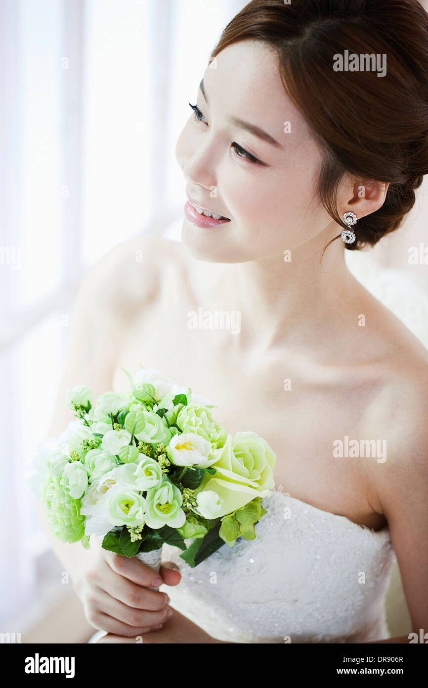 a woman posing with wedding dress and flower bouquet Stock Photo