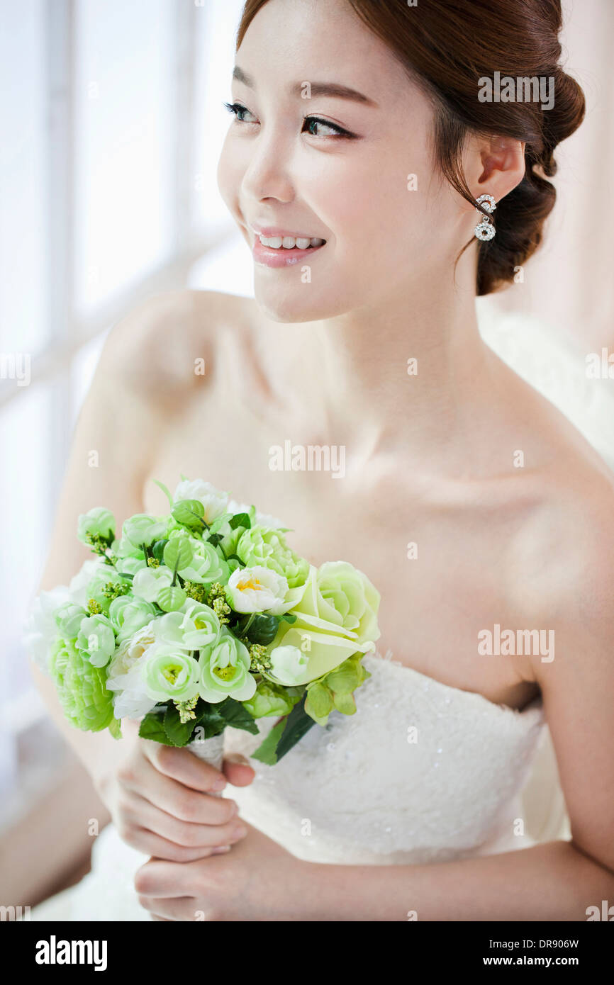 a woman posing with wedding dress and flower bouquet Stock Photo