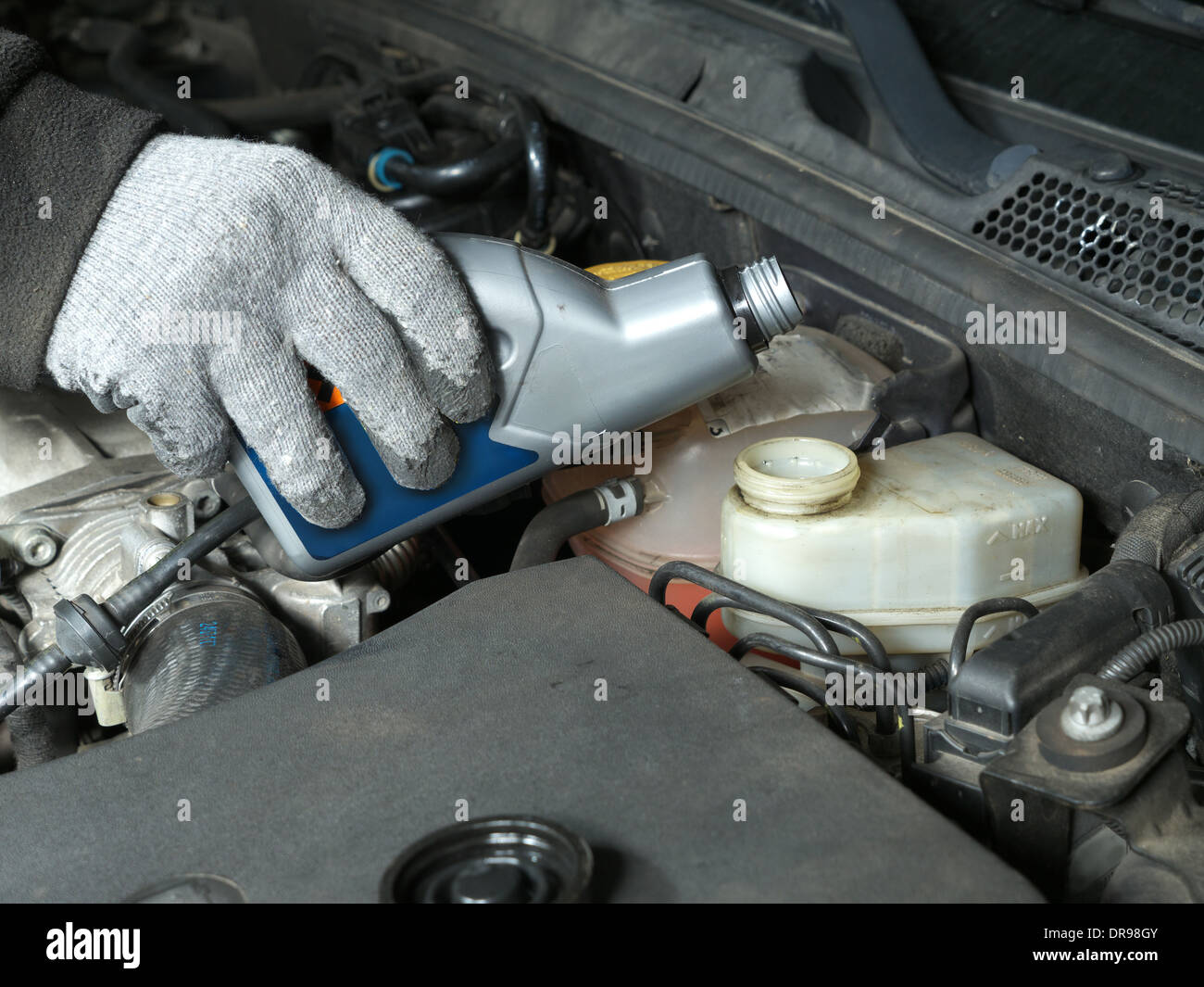 Auto mechanic topping up brake fluid in the vehicle Stock Photo