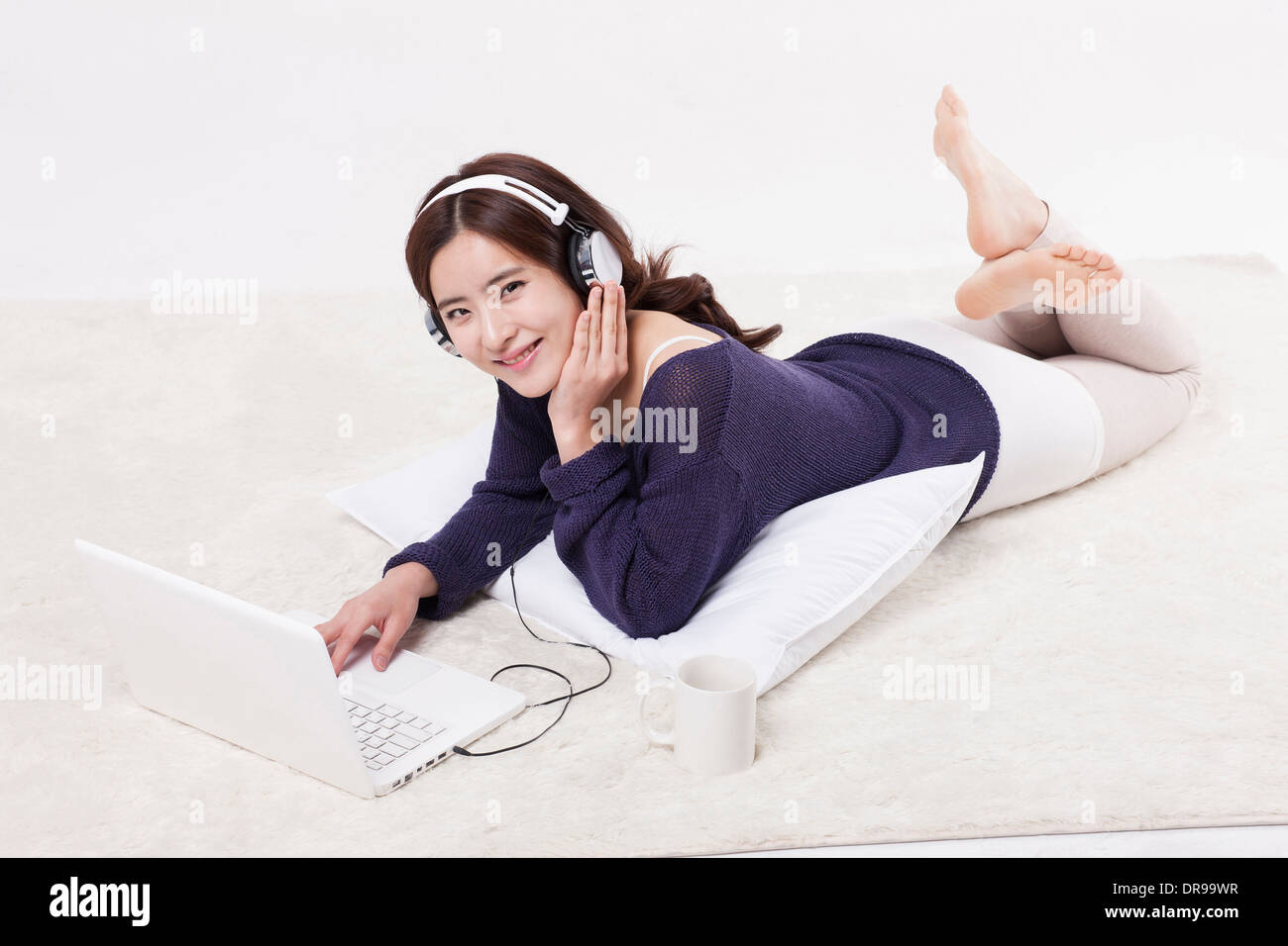 a woman lying on a carpet listening to music Stock Photo - Alamy