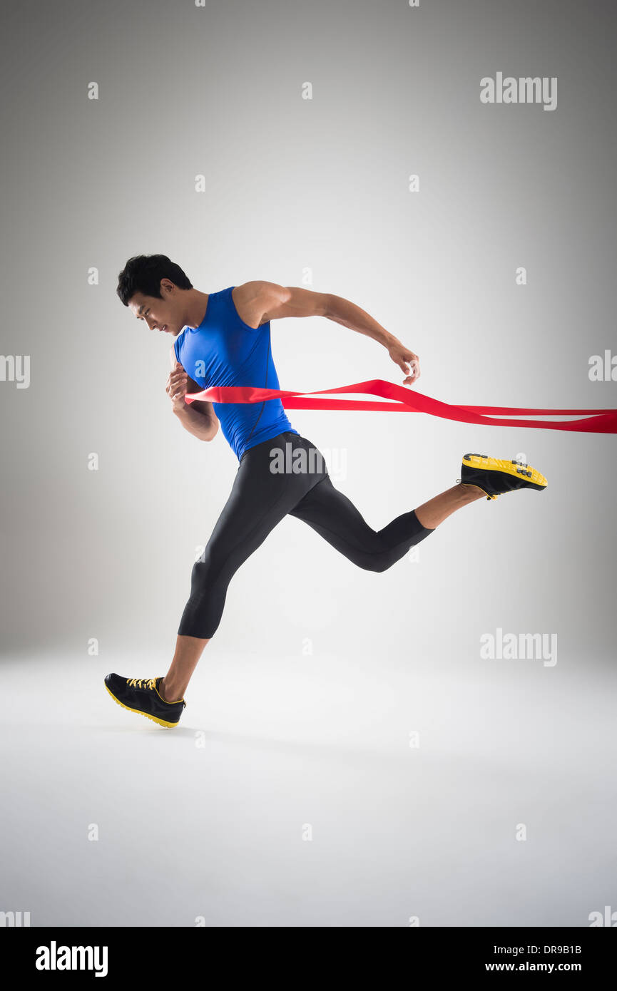 side shot of a fit man in blue shirt running to a finishing line Stock Photo