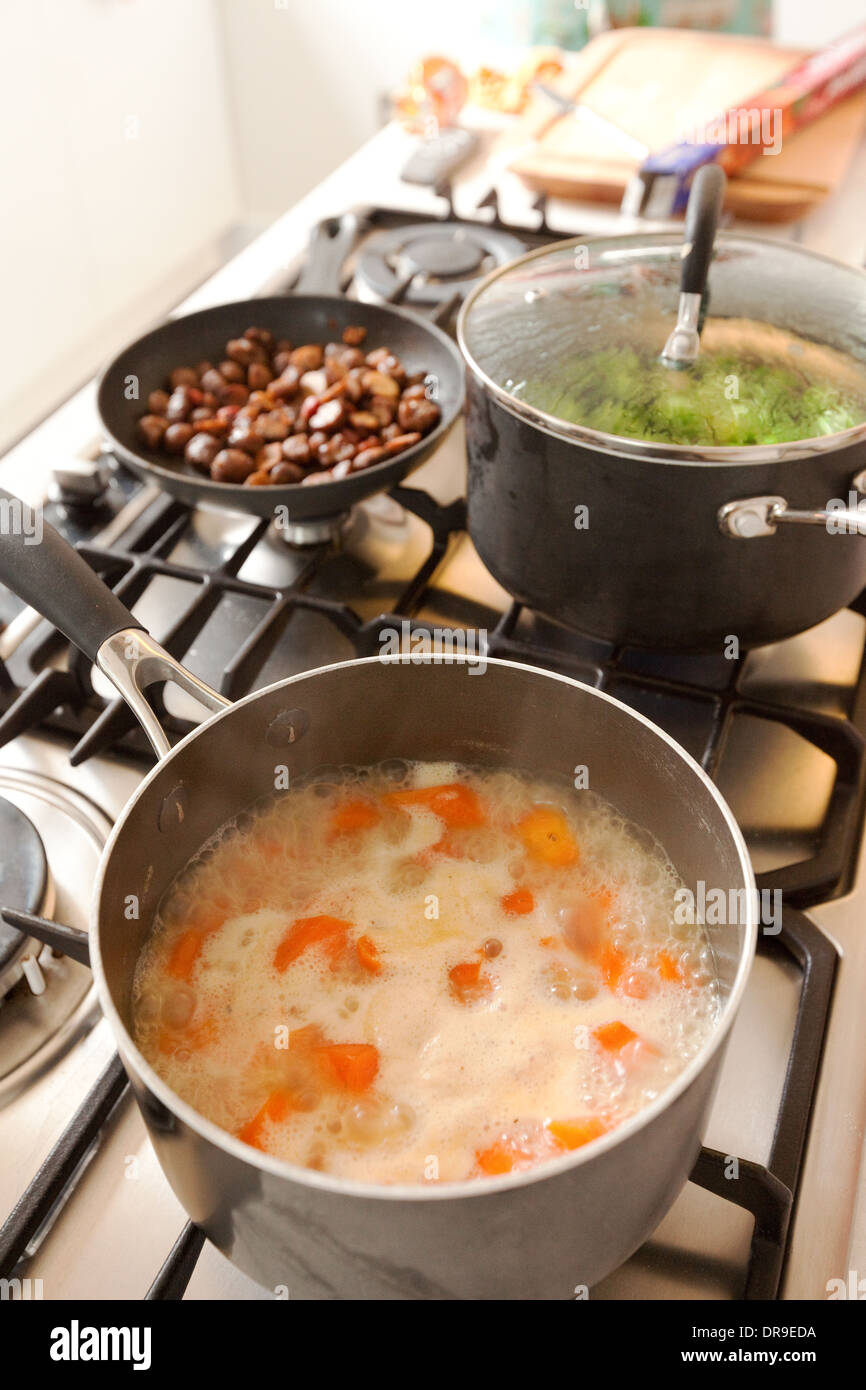 Carrots cooking boiling on the hob with brussel sprouts and chestnuts at Christmas, UK Stock Photo