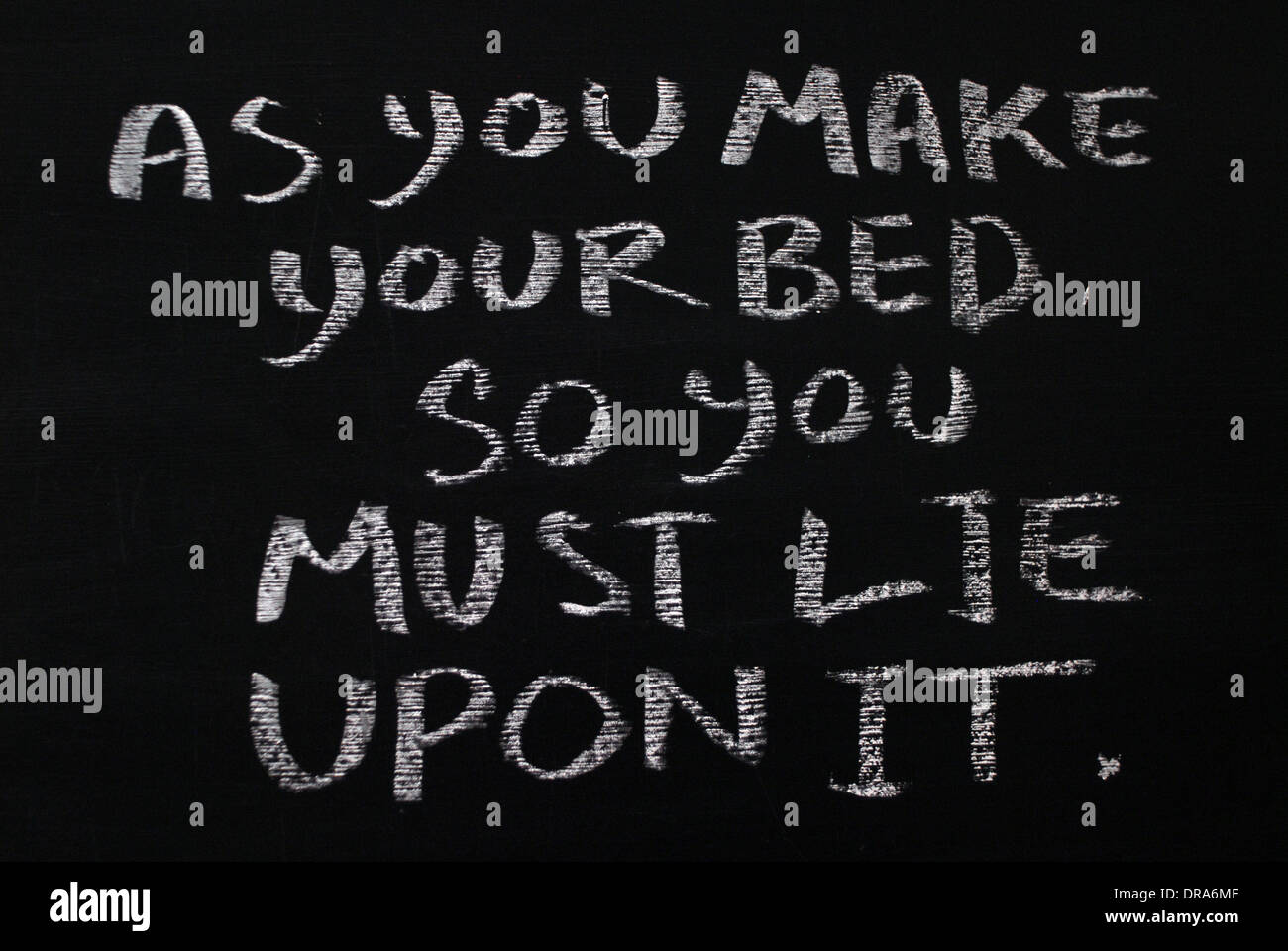 chalk writing - As you make your bed, so you must lie in it.- words written on blackboard. Stock Photo