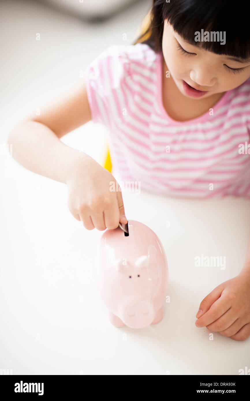 a girl putting money into piggy bank Stock Photo - Alamy